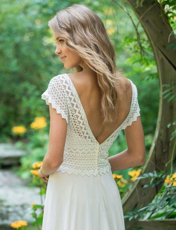 Dunkelblonde Braut mit fließendem Brautkleid und V-Ausschnitt Rückenansicht in Natur