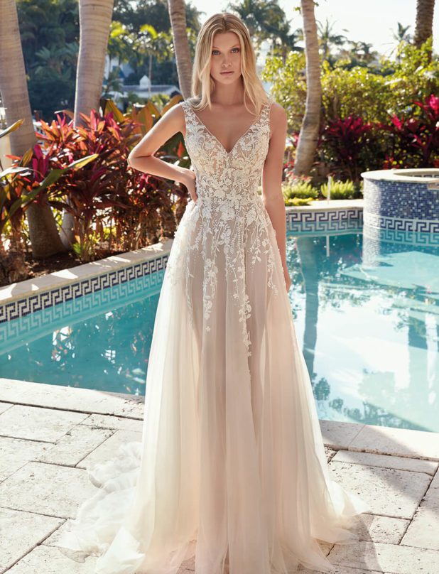 Blonde Braut in Brautkleid vor Pool im Garten