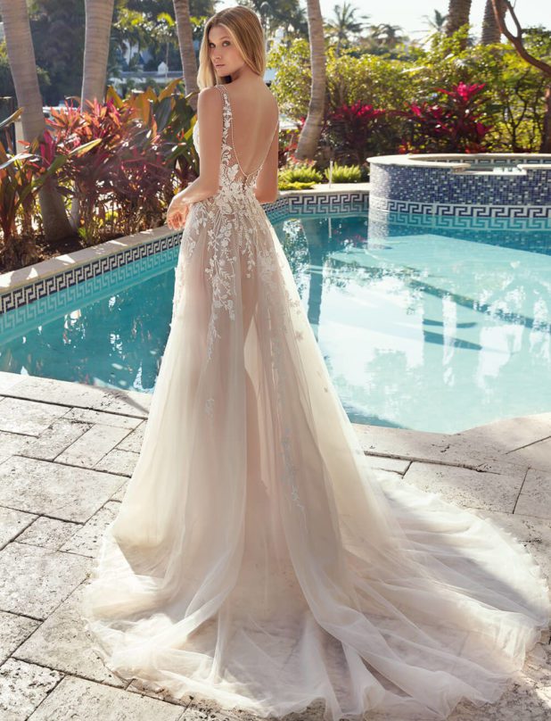 Blonde Braut in Brautkleid vor Pool im Garten Rückenansicht