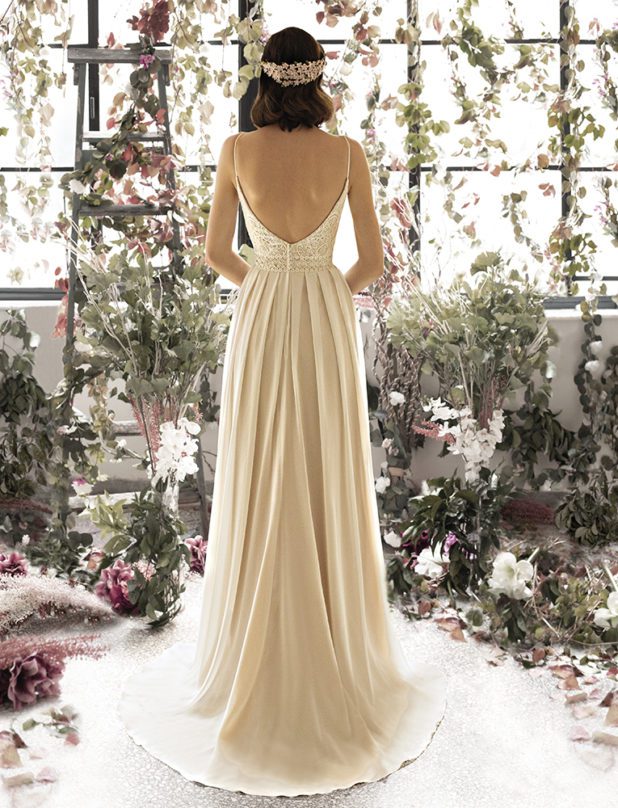 Schwarzhaarige Braut in Brautkleid A-Linie ärmellos Spaghettiträger mit weißen und rosanen Blumen sowie Blättern Rückenansicht und Kleid zwischen den Fingern