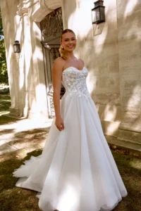 Elegantes Brautkleid mit bestickter Corsage und fließendem Tüllrock in einer stilvollen Outdoor-Kulisse fotografiert.