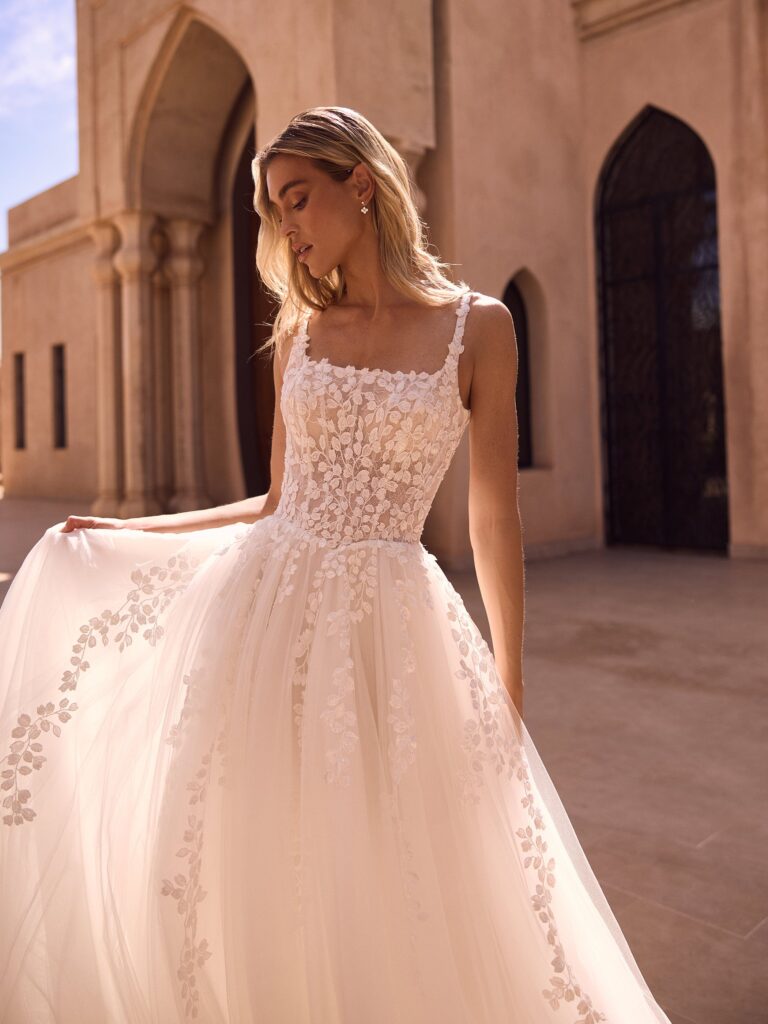 Nahaufnahme eines Brautkleid-Oberteils mit floraler Blätter-Spitze auf transparentem Tüll und quadratischem Ausschnitt.